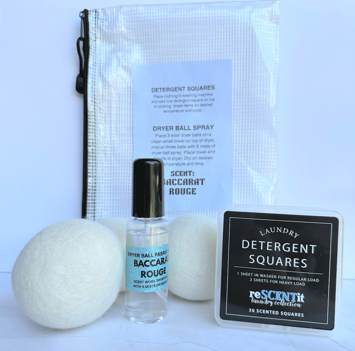 Laundry products including dryer balls, spray bottle, and detergent squares on a light blue background