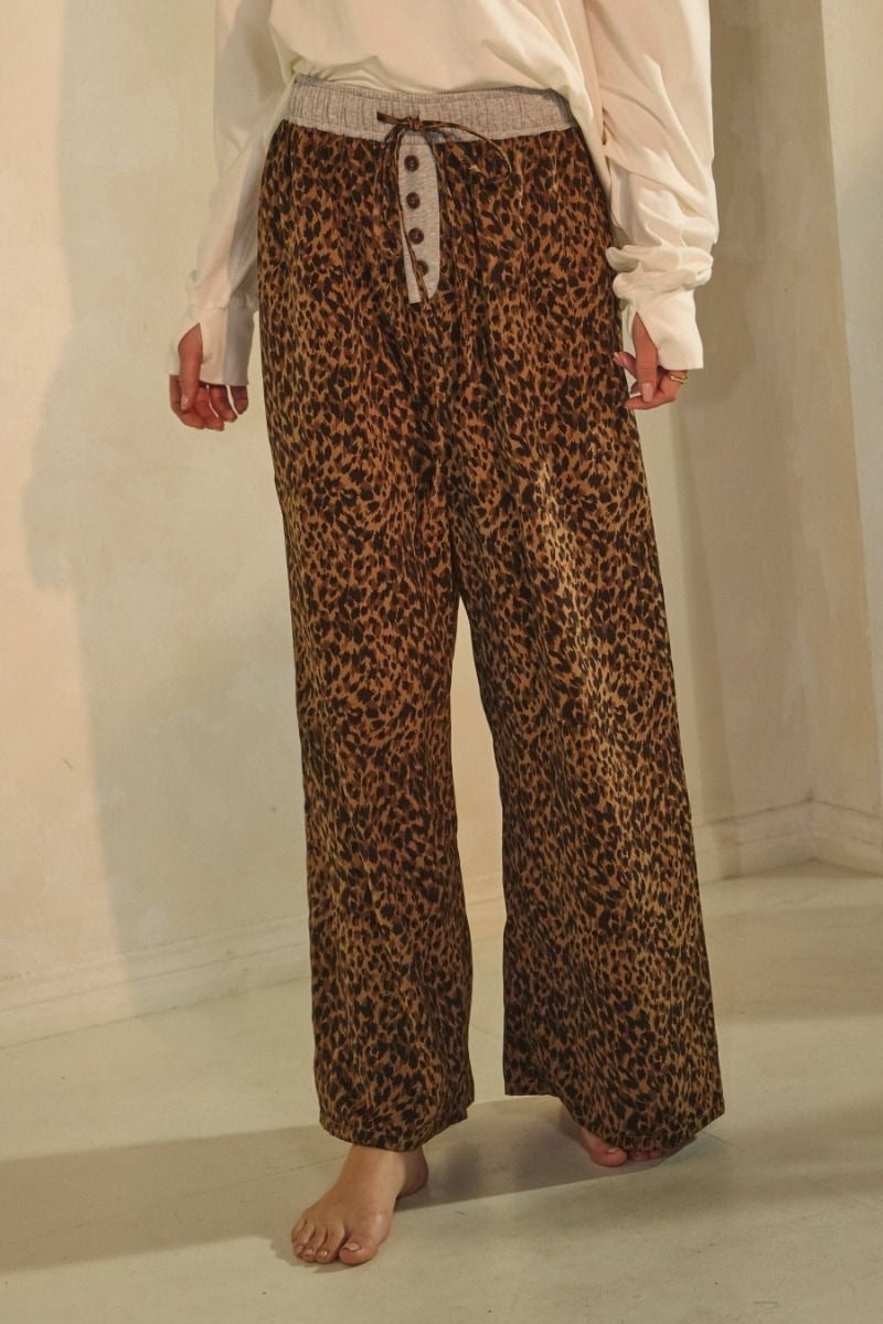 Leopard print wide-leg pants featuring an elastic waistband with button detail and relaxed fit