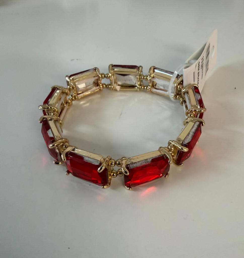 A gold-plated bracelet featuring alternating red rectangular crystal links and clear rectangular crystal links, shown on a plain light gray background with a white retail tag attached.