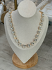 A gold-tone statement necklace with clear faceted rhinestones displayed on a beige fabric jewelry bust stand.