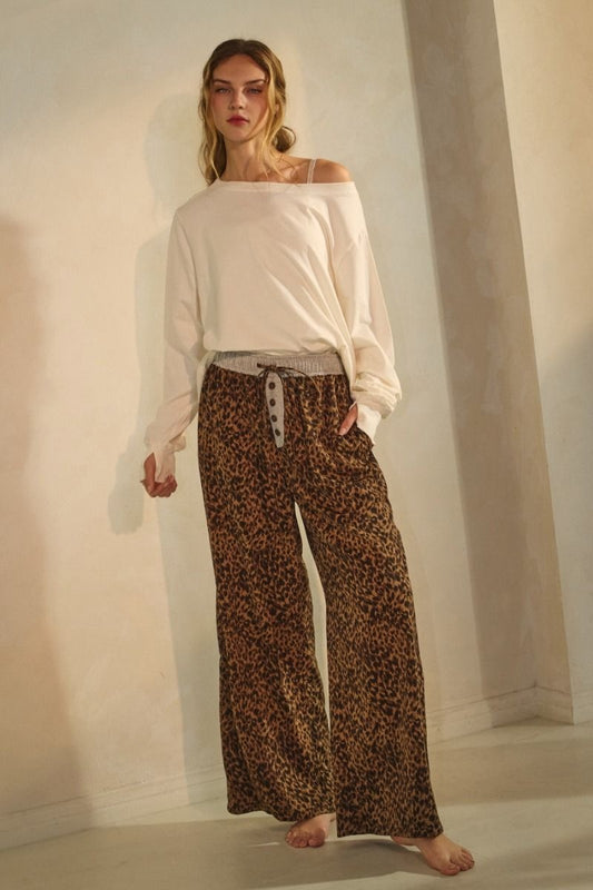 Leopard print wide-leg pants featuring an elastic waistband with button detail and relaxed fit